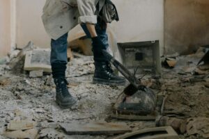 Rugged individual breaking outdated electronics in a derelict, dusty interior.